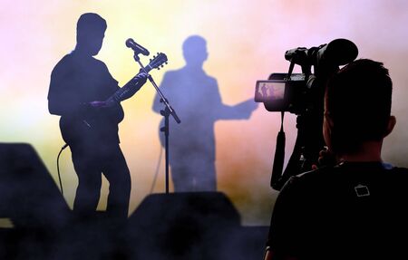 Cameraman recording and broadcasting live concerts on on stage using video camera.の写真素材