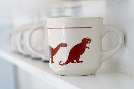 Cups lining up with dinosaurs printed on them. Leader and follower, rules and management conceptの写真素材