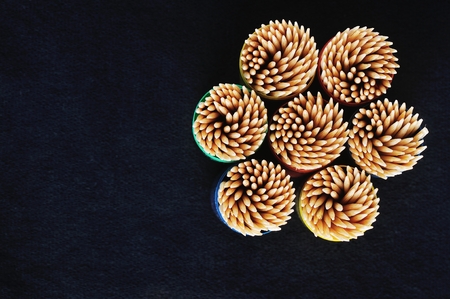 toothpicks in colorful plastic container on plain, black backgroundの写真素材
