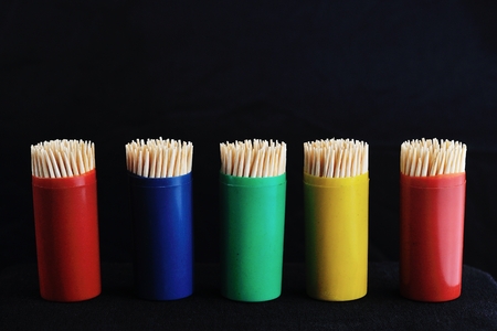 toothpicks in colorful plastic container on plain, black backgroundの写真素材