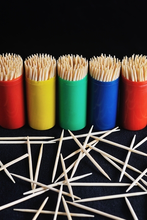 toothpicks in colorful plastic container on plain, black backgroundの写真素材
