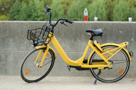 Yellow bike from bike sharing company parked next to the wall with drink and plastic cupsの写真素材