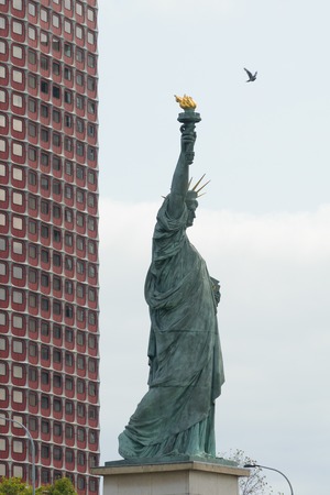 Statue of liberty in Paris, France with tall building in the backgroundの写真素材