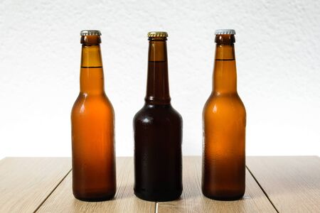 Cold beer bottle without label on wooden table back-lit isolated on white backgroundの写真素材