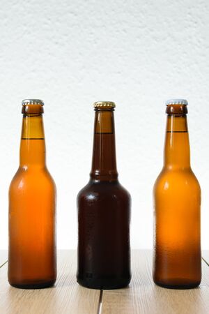 Cold beer bottle without label on wooden table back-lit isolated on white backgroundの写真素材