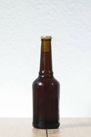 Cold beer bottle without label on wooden table back-lit isolated on white backgroundの写真素材