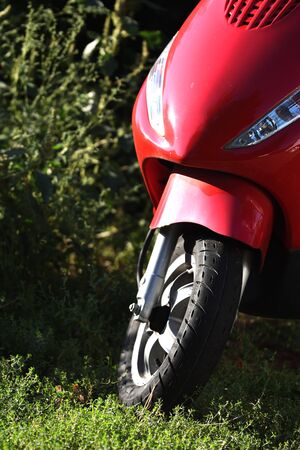 Close up of the front of a parked red scooterの写真素材