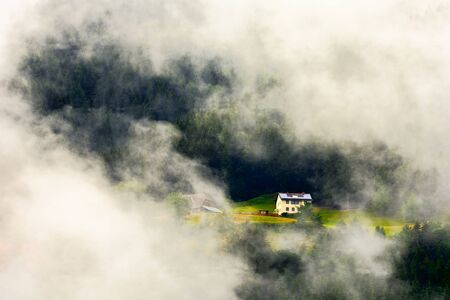 House in a high altitude european forest in a summer foggy, misty dayの写真素材