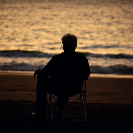 Silhouette of elderly woman sitting on a chair at the beach.の写真素材