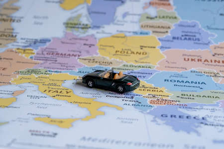 Toy car on Europe map, side view, teenager travel concept, miniature green sport car going to Italy, worldwide tour, map ideaの写真素材