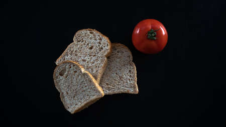 Rye bread and tomato on a black background. Close-up.の写真素材