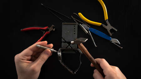 Close-up of hand holding pliers and tools on black background