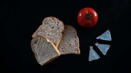 Sliced bread and red tomato with triangle cheese, lay down on table, concept food, bread slices with tomato isolated on black background, top viewの写真素材