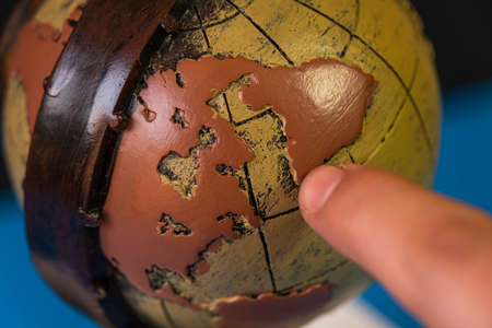 Close-up of a hand holding a wooden globe with a pattern