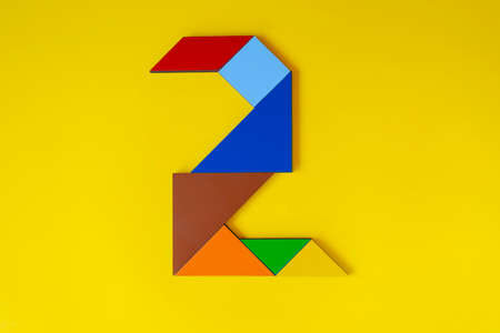 Colorful origami number 2 on a yellow background. Minimal concept.