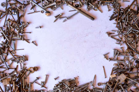 Frame made of various screws on a pink background. Place for text.