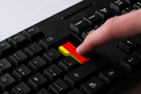 Close-up Of Person's Hand Pressing Computer Keyboard Button With German Flag