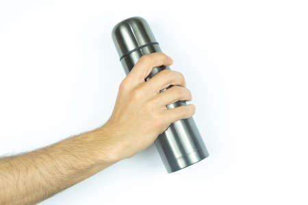 Man's hand holds a metal thermos on a white background.の写真素材