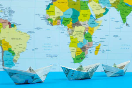 Paper boat origami on world map background. Travel and tourism concept
