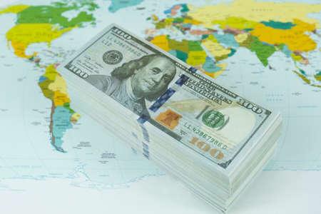 A stack of dollars on the background of the world map. Close-up