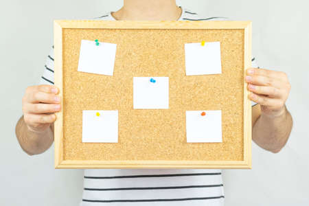 Woman holding a cork board with sticky notes in front of herの写真素材