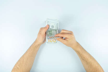 Top view of male hands counting dollar banknotes on white background.
