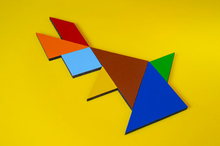 Paper tangram puzzle in red, blue and green on yellow backgroundの写真素材
