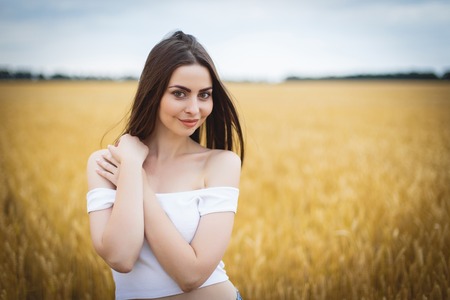 woman is walking in golden field of wheatの写真素材