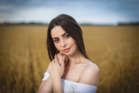 woman is walking in golden field of wheatの写真素材
