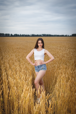 woman is walking in golden field of wheatの写真素材