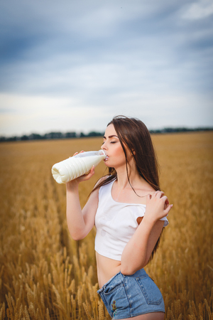 Beautiful woman is drinking milk in countrysideの写真素材