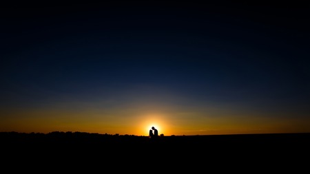 Silhouette of a loving couple over sunset backgroundの写真素材