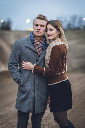 lovers close up emotional portrait. man hugs women. beautiful lovely fashionable trendy stylish couple hugging kissing. man in coat and scarf with woman in coat. lovers leaned touched foreheadsの写真素材