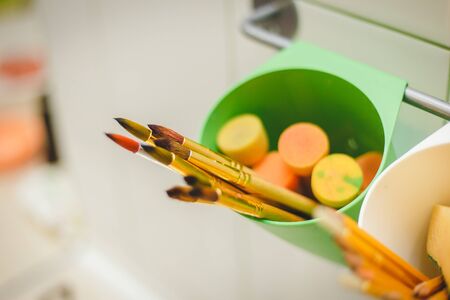 Drawing classes tools in art studio. Angle top above view photo of paintbrushes lying on palettewith oil paints brushstrokes mixture big tasselsの写真素材