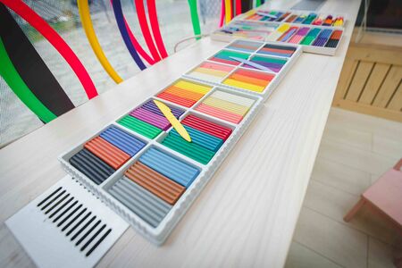 new only openened multi-colored colorfull clay plasticine lies. wide angle img photo of clay plasticine in drawing room lesson classes in school or kindergarten or education centre. Draw atmosphereの写真素材