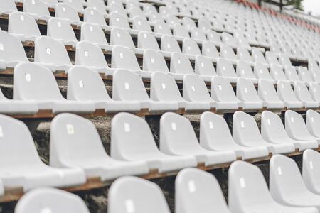 Stadiums amphitheater with many empty white plastic numbered seats for spectators in the stadium for football sport fans. Pattern of plain monochrome sport tribune.の写真素材