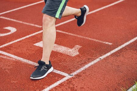 man in black shoes crosses the mark or finish line on running court or treadmill. Great solemn moment of final crossing final line.の写真素材