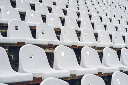 Stadiums amphitheater with many empty white plastic numbered seats for spectators in the stadium for football sport fans. Pattern of plain monochrome sport tribuneの写真素材