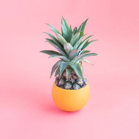 Pineapple mixing with orange on pink pastel color background.