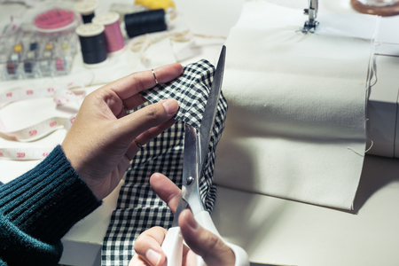 Close up fashion designer cutting cloth with equipment.top viewの写真素材