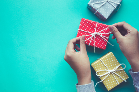 Female decorating cute gift box presents on worktable background.For christmas,new year,birthday and happiness concepts ideasの写真素材