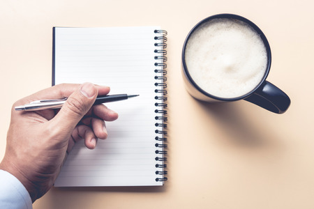 Male hand with notepad and coffee cup on desk  table backgrounds.の写真素材