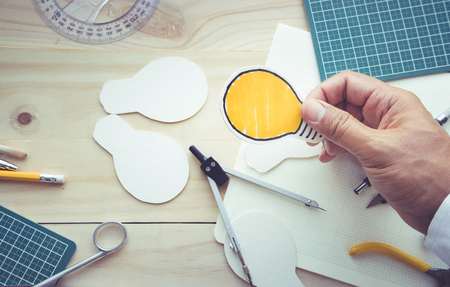 Top view of male hand holding light bulb paper with elements of tools,equipment.Creativity decoration design and handmade conceptsの写真素材