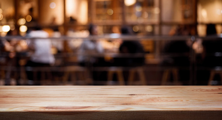 Wood table top on blurred of cafe ( restaurant ) with light gold in dark nigh background.panoramic...