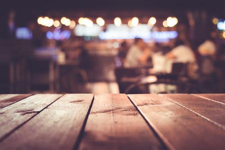 Wood table top with blur light bokeh in dark night cafe,restaurant background .Lifestyle and...
