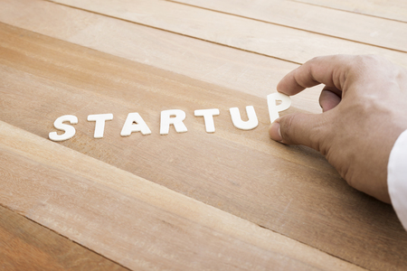 Startup word with male hand on wood table.Business marketing,analysis conceptsの写真素材