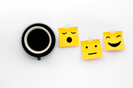 Wake up concepts with coffee drink and emoticon face on notepaper on white background.