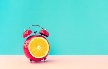 Summer time concepts ideas with orange alarm clock on blue pastel background.