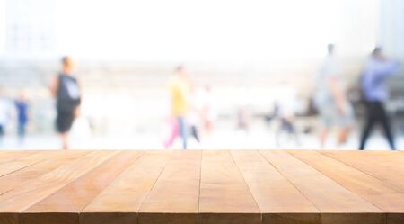 Wood table top with blur of people in walkway office building .background for product display