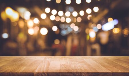 Wood table top with blur of lighting in night street cafe(community).selective focus.celebration...